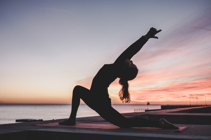 A person doing yoga on a pier